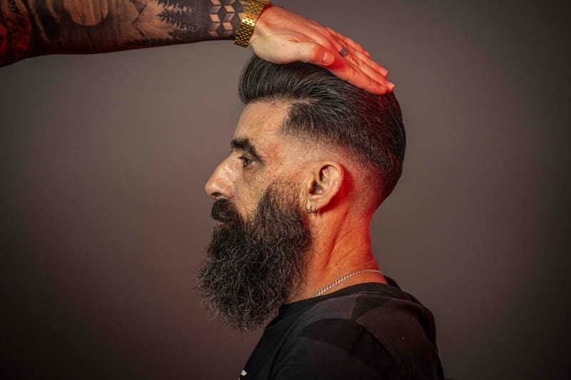 Barbero comprobando un degradado con barba larga